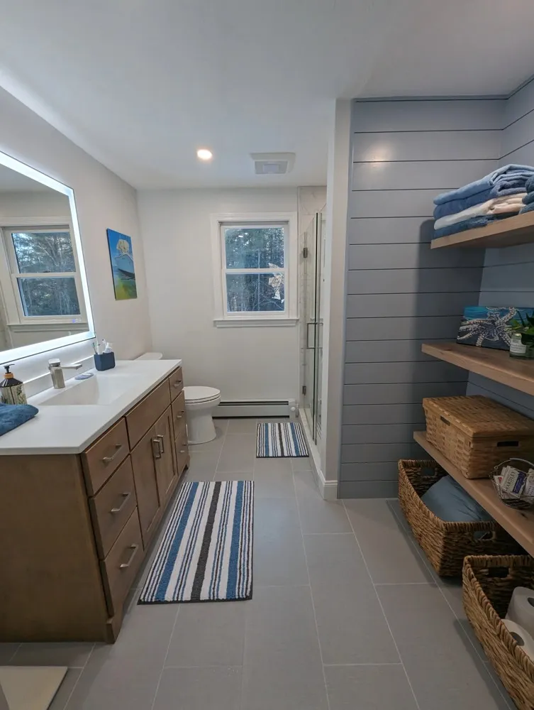 Remodeled bathroom with wood vanity, shiplap wall and open shelving