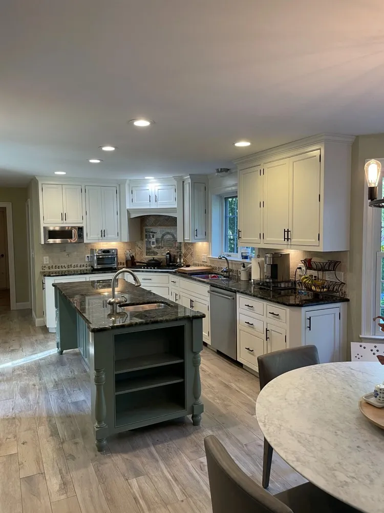 Kitchen with refinished cabinets and a green island