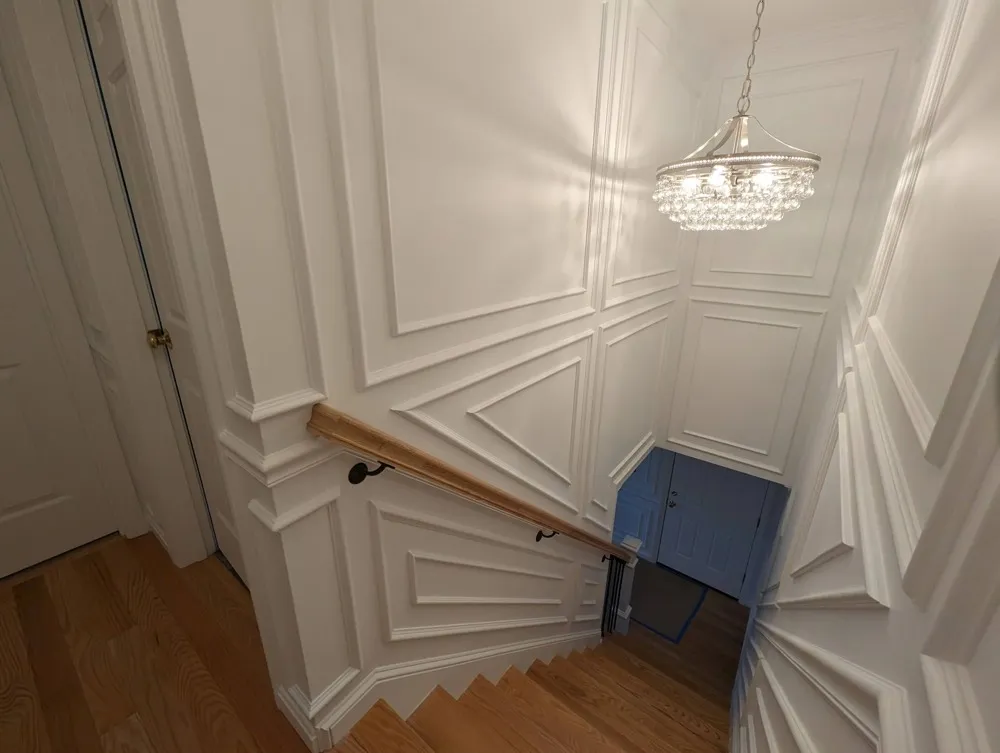 Stairwell and living room wainscoting with a chandelier